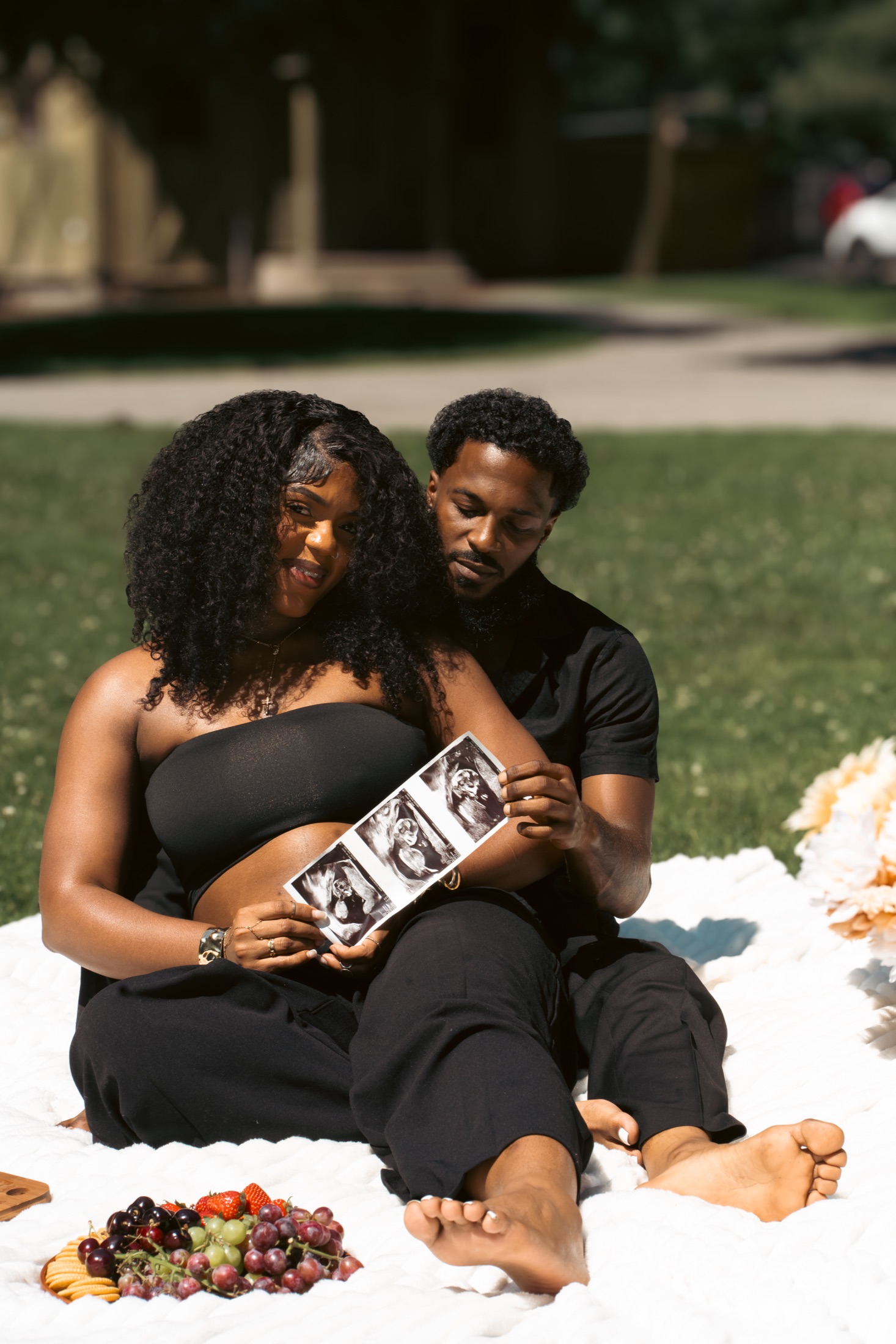 Expecting parents holding ultrasound photos during an outdoor maternity session