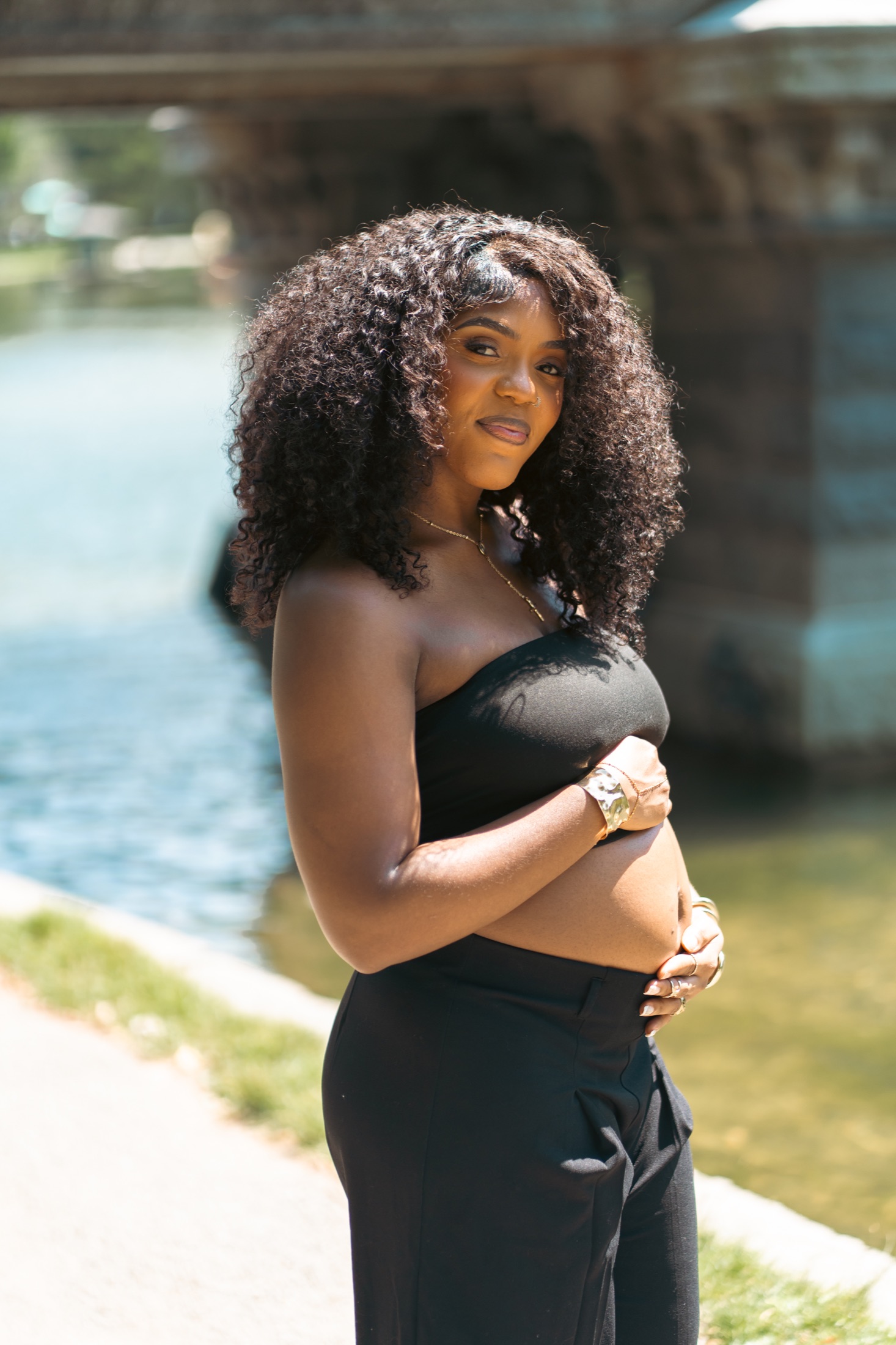 Expecting mother photographed beside a calm outdoor water setting