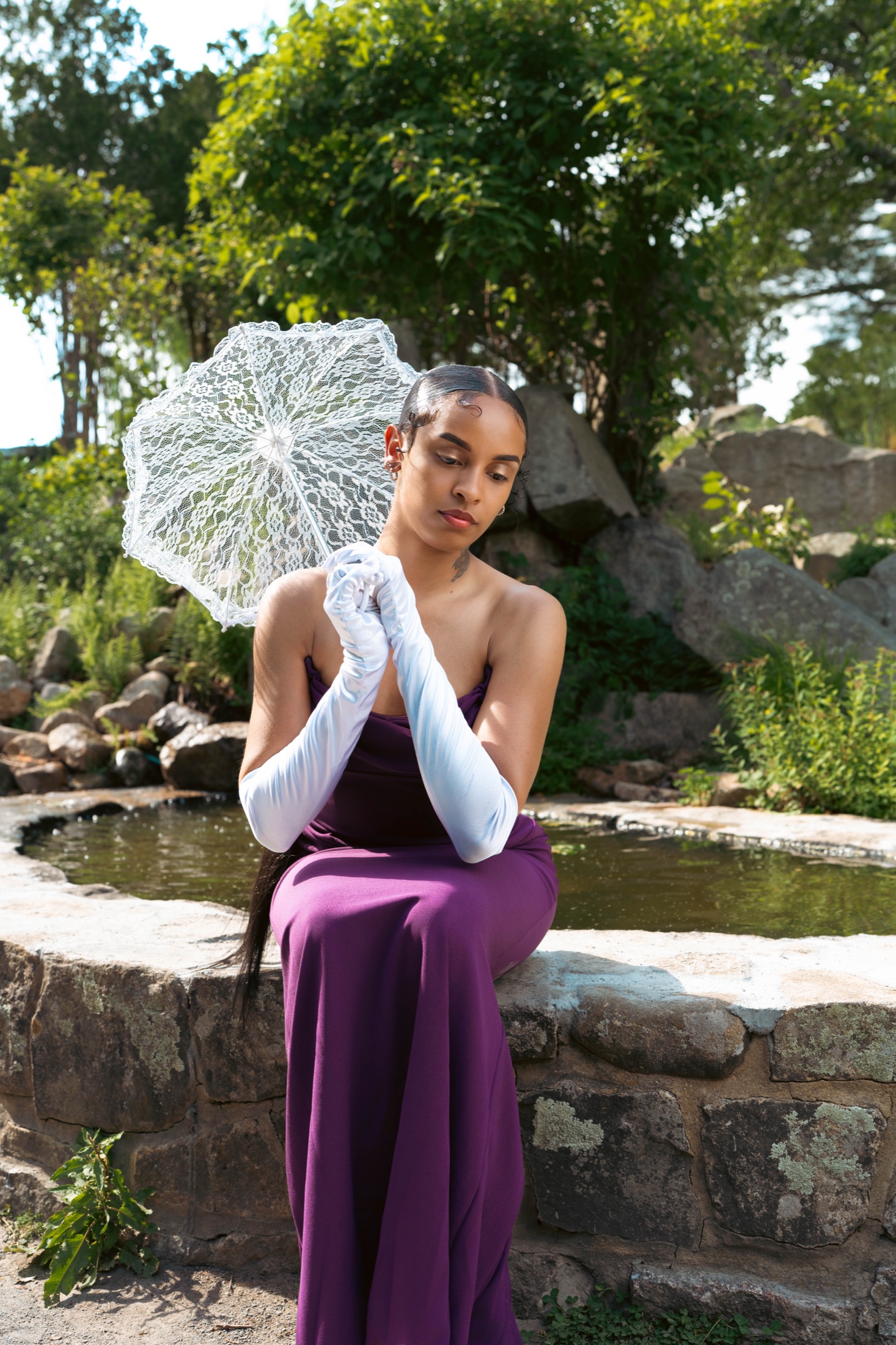 Portrait subject in a purple dress posed beside a creek